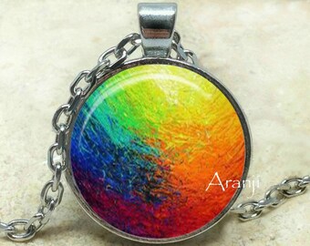 May include: A silver chain necklace with a round glass pendant featuring an abstract painting of a rainbow with shades of blue, green, yellow, orange, and red.