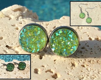 May include: A pair of green glitter stud earrings and a pair of green glitter dangle earrings. The earrings are made with a silver metal setting.