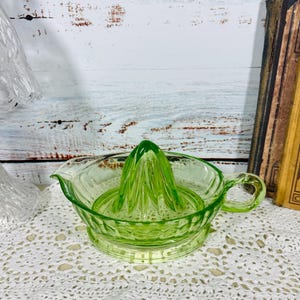 Peut inclure: Un presse-agrumes en verre vert clair doté d'un cône central, d'un large bol avec des nervures verticales, d'un petit bec verseur sur un côté et d'une anse incurvée sur le côté opposé, le tout fabriqué en verre pressé translucide.