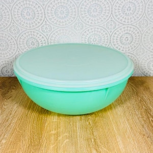 Puede incluir: Un tazón mezclador redondo de plástico color verde menta con una tapa circular a juego en un tono verde menta más claro. El tazón presenta un exterior liso de color sólido y un borde ancho, diseñado para almacenar o preparar alimentos.