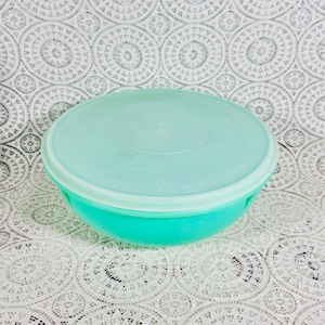 Könnte beinhalten: Eine runde, türkisfarbene Kunststoffschüssel mit passendem Deckel. Die Schüssel hat eine leicht strukturierte Oberfläche und einen weißen Rand. Der Deckel ist glatt und passt gut. Die Schüssel ist wahrscheinlich zur Aufbewahrung von Lebensmitteln.