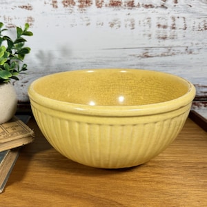 Puede incluir: Un tazón mezclador de cerámica amarillo con un diseño acanalado. El tazón está vacío y tiene un acabado brillante.