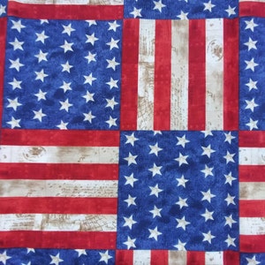 May include: A patchwork fabric featuring a repeating pattern of the American flag in red, white, and blue. The fabric is made of a soft, woven material and has a vintage look.