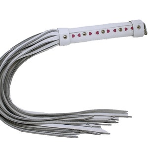 May include: White leather whip with a pink heart design and silver studs. The whip has a long handle and a fringed end.