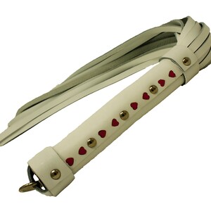 May include: White leather whip with a red heart design and gold studs.