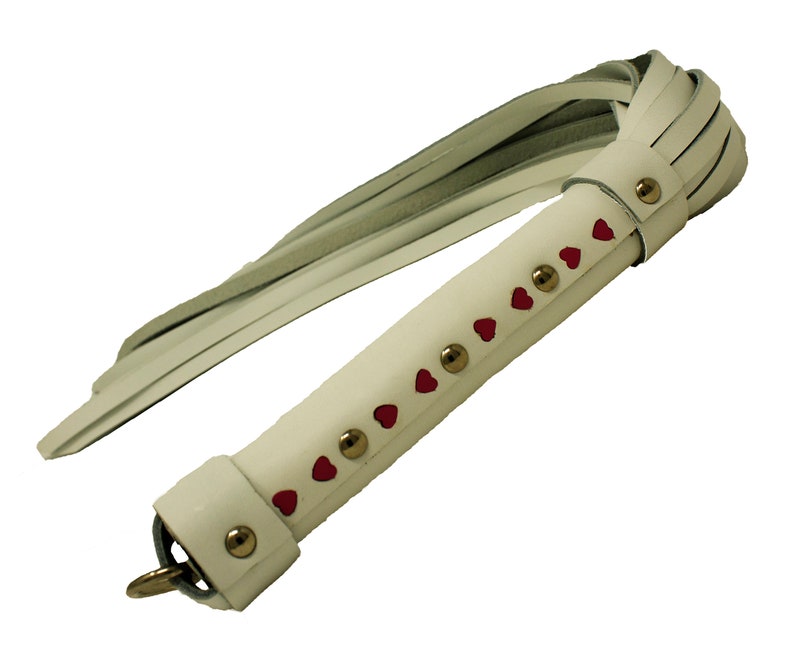 May include: White leather whip with a red heart design and gold studs.