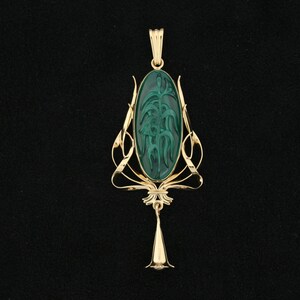 Puede incluir: Un colgante de oro con una piedra verde que presenta un dise&ntilde;o floral tallado. El colgante es de estilo Art Nouveau.