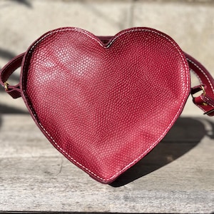Monedero de piel roja hecho a mano con forma de corazón, costuras blancas, cremallera dorada y correa ajustable