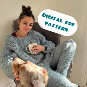 May include: A person wearing a light blue knit sweater and matching pants, holding a mug. The image includes the text "DIGITAL PDF PATTERN" in a white oval. A dog is looking up at the person.