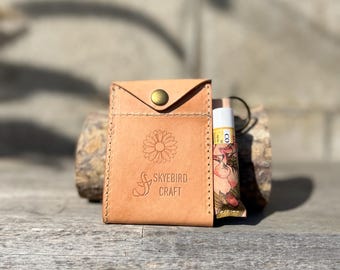 May include: A small, tan leather pouch with a snap closure and a floral design. The pouch has the text "Skybird Craft" embossed on the front.