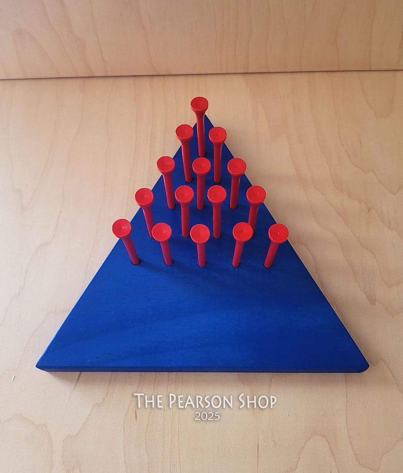 May include: A blue wooden triangle with red pegs arranged in a triangular pattern. The pegs are evenly spaced and have a rounded top. The wooden base has the text "THE PEARSON SHOP 2025" printed on it.