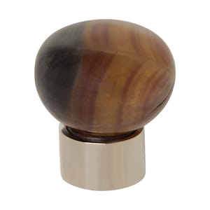 Op de afbeelding: Een ronde, gestreepte, bruin en zwarte decoratieve knop met een zilveren voet.