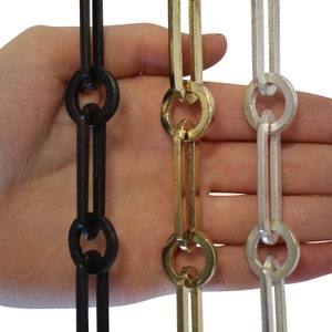 May include: Three chains of different finishes: black, gold, and silver. Each chain is made of linked, rectangular pieces with rounded ends.