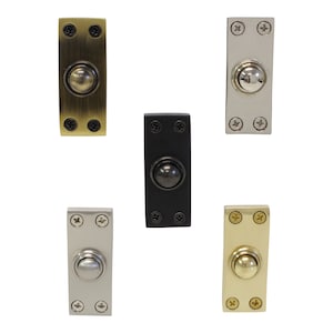 May include: Five doorbell buttons in different finishes: brass, polished nickel, satin nickel, black, and gold. Each button has a round, raised center.
