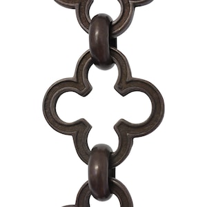 May include: Close-up of a decorative chain with a repeating quatrefoil design. The chain links are a dark bronze color, with a matte finish. The links are connected by oval-shaped connectors.