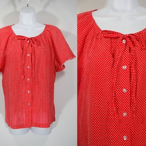 May include: A red button-down blouse with white polka dots and a bow tie at the neckline. The blouse has short sleeves with scalloped edges.
