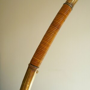 May include: A gold-colored metal lamp base with a brown woven rattan covering.