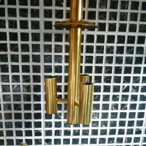 Puede incluir: Una l&aacute;mpara de techo de metal dorado con tres bombillas. La l&aacute;mpara tiene un dise&ntilde;o simple y geom&eacute;trico y est&aacute; suspendida del techo por una cadena.