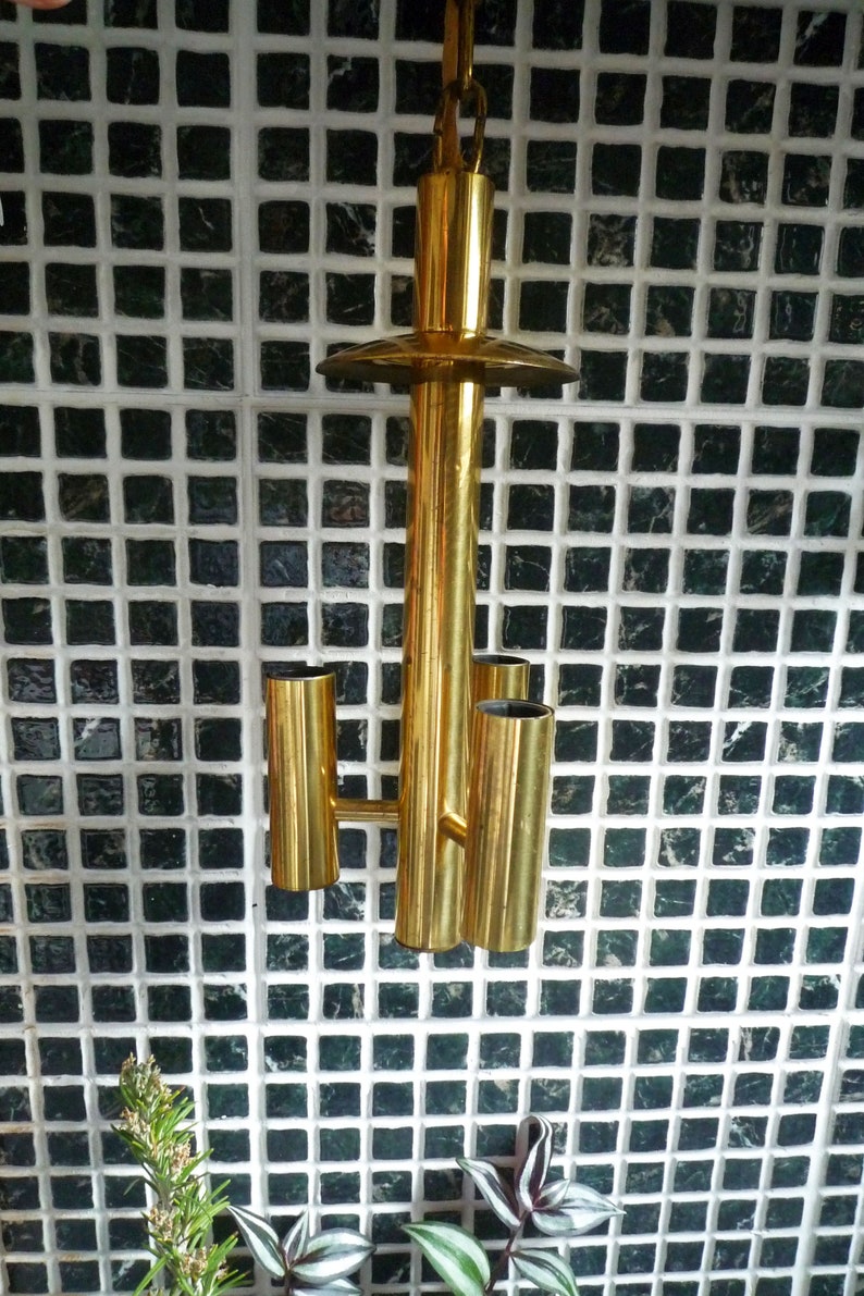 Puede incluir: Una l&aacute;mpara de techo de metal dorado con tres bombillas. La l&aacute;mpara tiene un dise&ntilde;o simple y geom&eacute;trico y est&aacute; suspendida del techo por una cadena.
