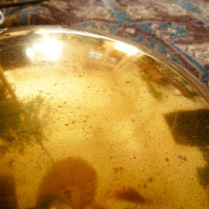 May include: A close-up of a gold-colored metal lampshade with a textured surface. The lampshade is reflecting light and has a warm, golden hue.
