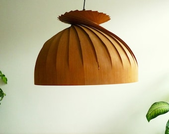 May include: A wooden pendant light with a spiral design. The light is hanging from a black cord and has a brown wood finish.