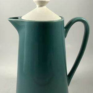 May include: A teal ceramic coffee pot with a white lid. The pot has a rounded body and a handle.