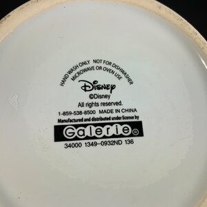 May include: White ceramic Disney-branded product with text: "HAND WASH ONLY, NOT FOR DISHWASHER, MICROWAVE OR OVEN USE." Includes the Disney logo and "Galerie" branding. Made in China.