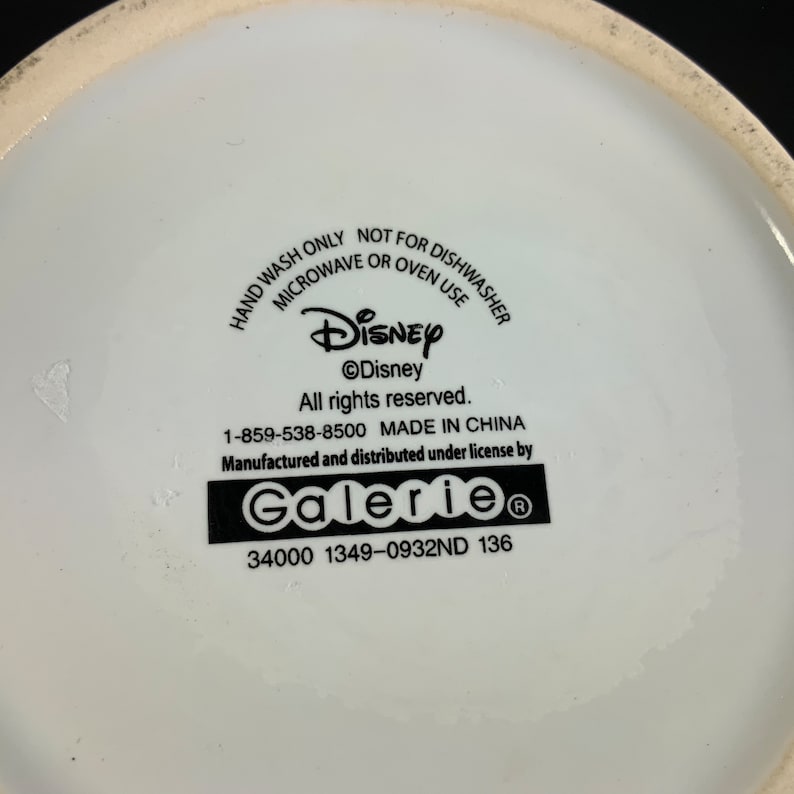 May include: White ceramic Disney-branded product with text: "HAND WASH ONLY, NOT FOR DISHWASHER, MICROWAVE OR OVEN USE." Includes the Disney logo and "Galerie" branding. Made in China.
