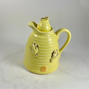 May include: Yellow ceramic honey pot shaped like a beehive with a lid and gold bee accents.