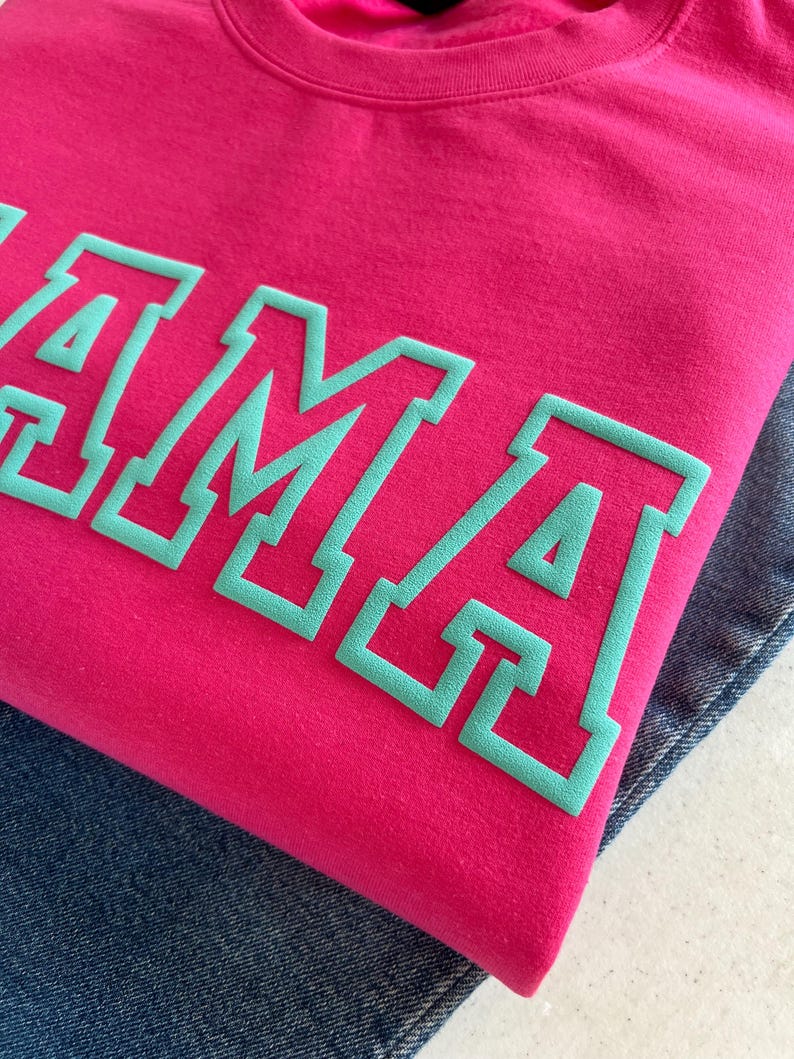 May include: A pink sweatshirt with the word "MAMA" in teal lettering.