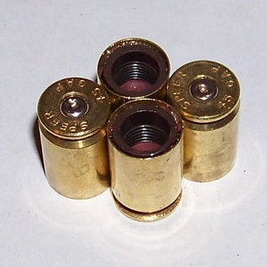 May include: Four gold-colored tire valve stem caps shaped like bullet casings. Each cap has a black rubber insert and the text "SUPER 9" is visible on one of the caps.