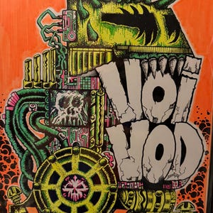 May include: An illustration with the text "Voivod" in a cracked, white font. The artwork features a complex, colorful design with green, yellow, pink, and black elements, including a skull and a gear-like structure, set against an orange background.