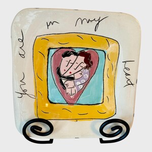 May include: A white ceramic dish with a yellow frame and a heart-shaped image of a couple embracing. The text "you are in my heart" is written on the dish.