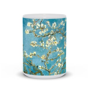 May include: White ceramic mug with a blue background and a painting of a blooming almond tree with white flowers. The painting is a reproduction of a famous artwork by Vincent van Gogh.