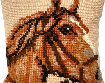 May include: A brown and white horse head embroidered on a beige pillow. The horse is wearing a black bridle.