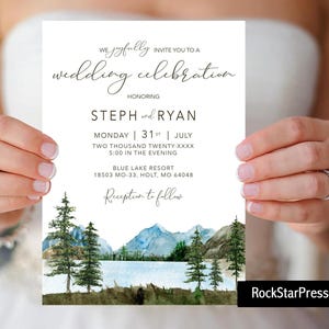May include: A white wedding invitation with a watercolor illustration of mountains, a lake, and pine trees. The invitation reads "We joyfully invite you to a wedding celebration honoring Steph and Ryan" and includes the date, time, and location of the wedding.
