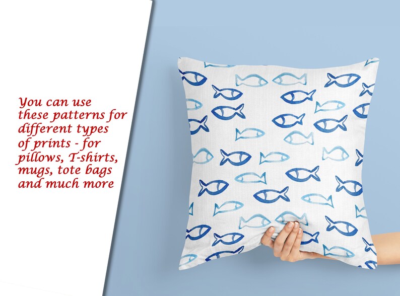 May include: A white pillow with a blue and white fish pattern. The pillow is being held by a hand.