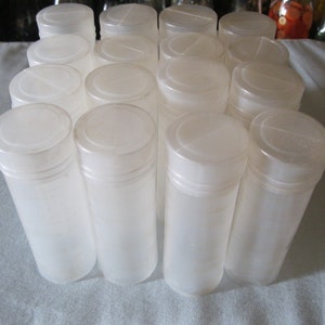 May include: A collection of translucent, cylindrical plastic tubes with white, snap-on lids. The tubes are arranged closely together, suggesting they are for storage or packaging. The lighting is soft, highlighting the smooth surfaces.