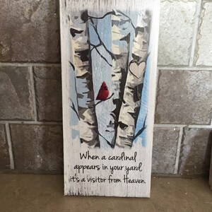 Puede incluir: Un letrero de madera con una imagen pintada de tres abedules, un cardenal rojo y dos corazones. El letrero tiene el texto "Cuando un cardenal aparece en tu jard&iacute;n, es un visitante del cielo."
