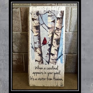 Puede incluir: Un letrero de madera con una imagen pintada de tres abedules y un cardenal rojo. El letrero tiene el texto "Cuando un cardenal aparece en tu jard&iacute;n, es un visitante del cielo." y un coraz&oacute;n con la palabra "DAD" dentro.