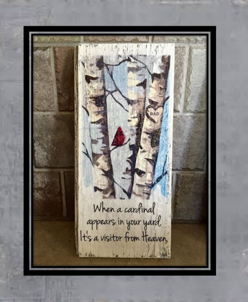 Puede incluir: Un letrero de madera con una imagen pintada de tres abedules y un cardenal rojo. El letrero tiene el texto "Cuando un cardenal aparece en tu jard&iacute;n, es un visitante del cielo." y un coraz&oacute;n con la palabra "DAD" dentro.