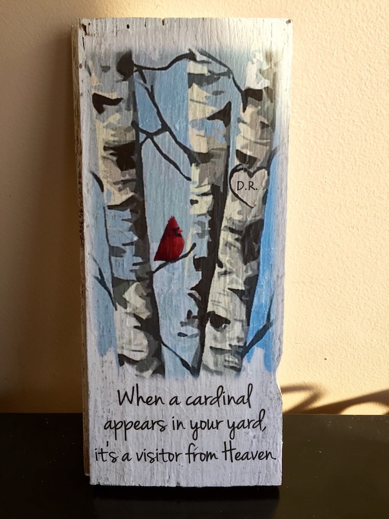Puede incluir: Un letrero de madera con una imagen pintada de tres abedules y un cardenal rojo posado en una rama. El letrero tiene el texto "When a cardinal appears in your yard, it's a visitor from Heaven." y un coraz&oacute;n con las iniciales "D.R." pintadas en &eacute;l.