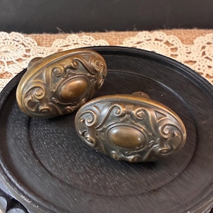Par de pomos de puerta victorianos antiguos de latón con diseño de espiral en relieve.