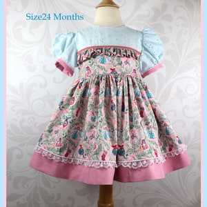 May include: A pink and blue dress with a Christmas print featuring ornaments, angels, and holly. The dress has a ruffled bodice and a lace trim. The dress is size 24 months.