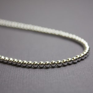 Peut inclure: Un collier en cha&icirc;ne argent avec de petites perles rondes.
