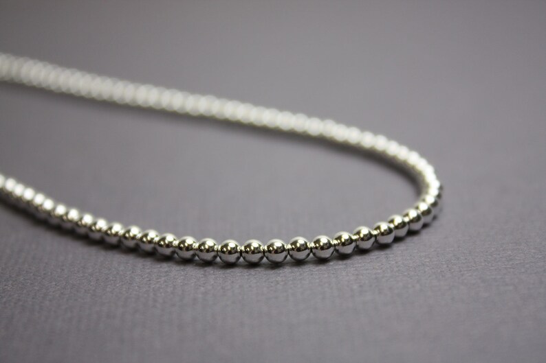 Peut inclure: Un collier en cha&icirc;ne argent avec de petites perles rondes.