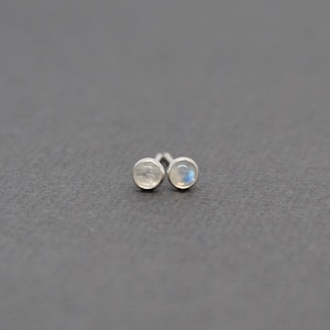 May include: A pair of silver stud earrings with small round moonstone gems.
