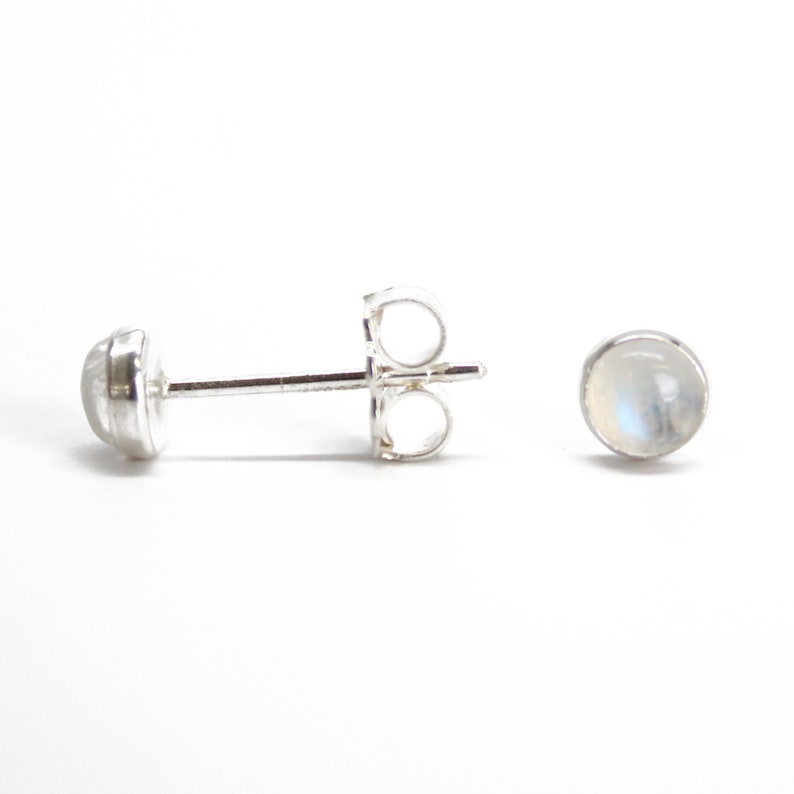 May include: A pair of silver stud earrings with round moonstone gemstones.