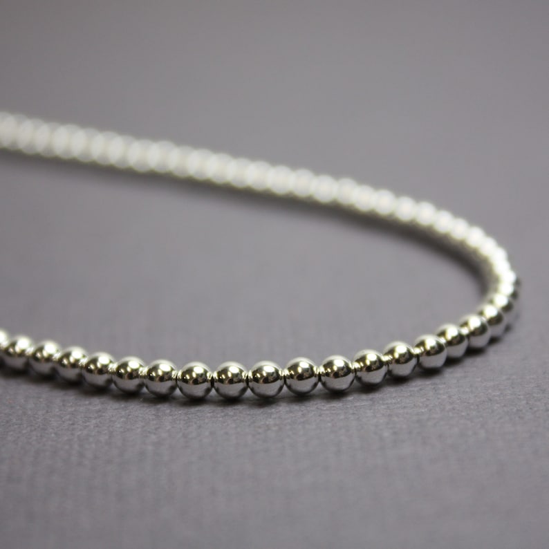 Peut inclure: Un collier de perles argent&eacute;es avec un design simple. Le collier est compos&eacute; de petites perles rondes uniform&eacute;ment espac&eacute;es.