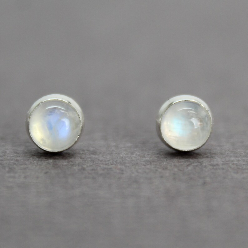 May include: A pair of silver stud earrings with round moonstone gemstones.